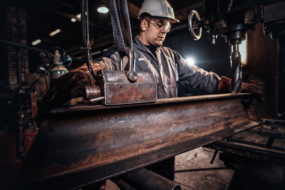 Worker handling a metal rail in a factory
